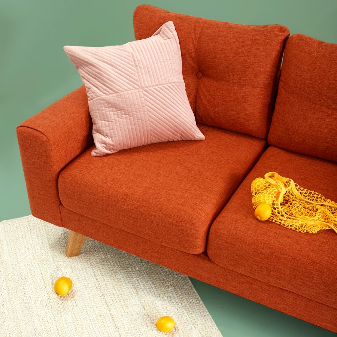An orange sofa against a green wall